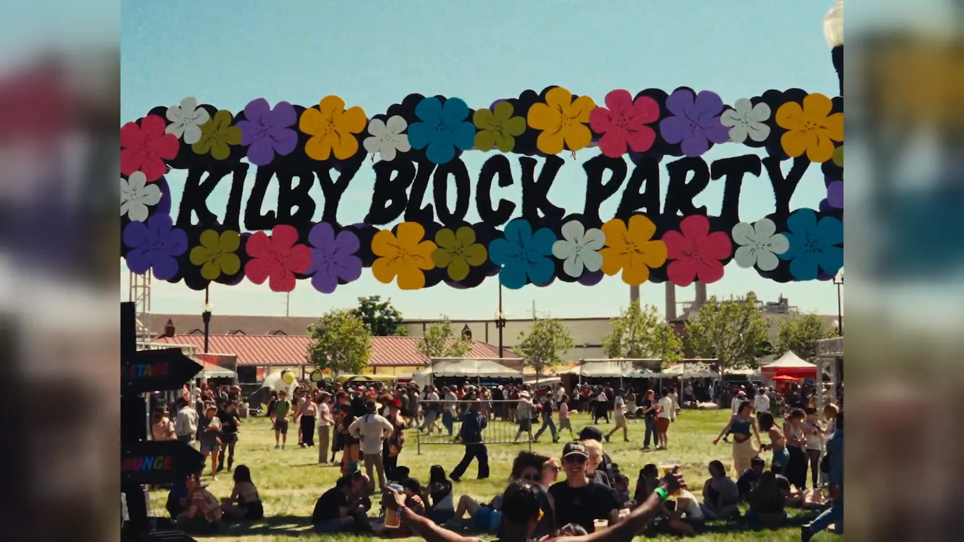 The flower-covered Kilby Block Party sign over a sunny festival lawn full of people